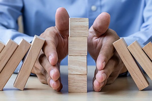businessman-hand-stopping-falling-wooden-blocks-or-dominoes